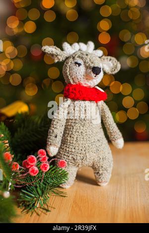 Il cervo giocattolo lavorato a maglia cute sullo sfondo dell'albero di Natale Foto Stock