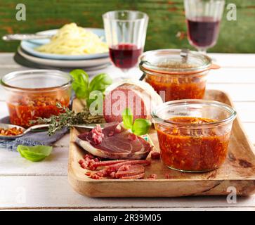 Salsa bolognese in vasetti di conservazione serviti con prosciutto di Parma e salame Foto Stock