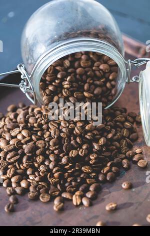 I chicchi di caffè cadono da un bicchiere Foto Stock