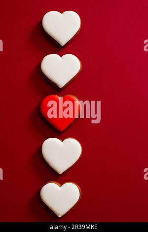 Biscotti di pan di zenzero in forma di cuore su sfondo rosso Foto Stock