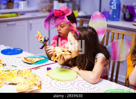 La bambina carina mangia la pizza a festa. Bella ragazza in costume farfalla. Festa di compleanno Foto Stock