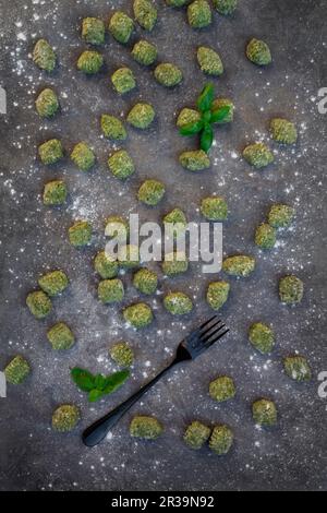 Spinaci freschi e gnocchi di basilico su una superficie grigia (vista dall'alto) Foto Stock