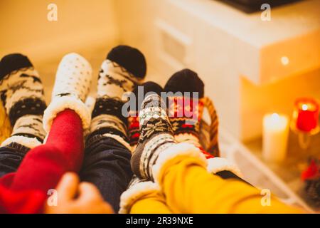 La grande famiglia si sta riscaldando vicino al caminetto Foto Stock