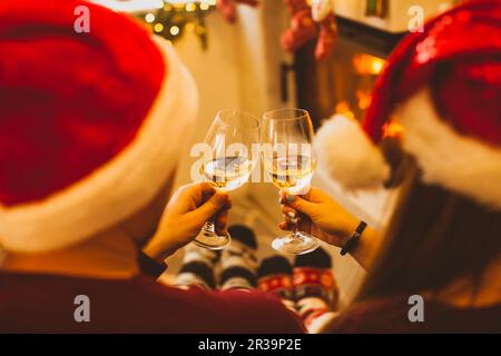 Vista sul retro coppia di Natale vicino al caminetto, tostatura Foto Stock