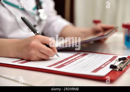 Il medico che tiene la compressa e scrive un'analisi a raggi X nella storia medica dei pazienti. Primo piano Foto Stock