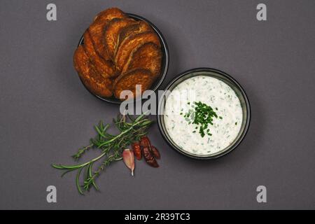 Vista panoramica sulle patatine dolci piccanti guarnite con peperoncino, rosmarino e timo e salsa condita all'aglio e yogurt in ciotole nere Foto Stock