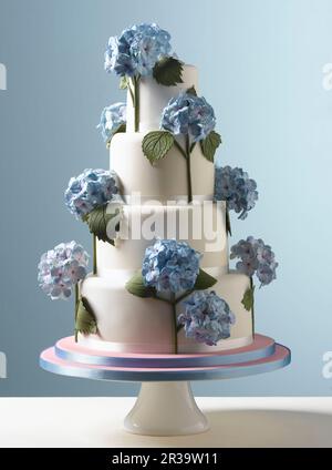 Feste di Pasqua, torta nuziale bianca a strati con fiori di idrangea blu con sfondo blu pallido Foto Stock