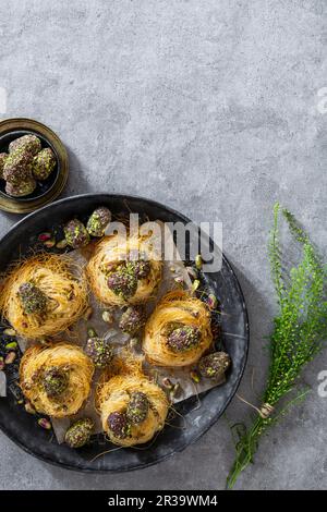 Uova di Pasqua rivestite in datteri, cacao e pistacchi in nidi di pasta pelo angelo Foto Stock