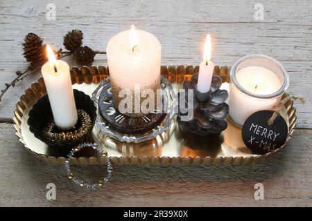 Quattro candele che bruciano con le decorazioni di Natale su un vassoio Foto Stock