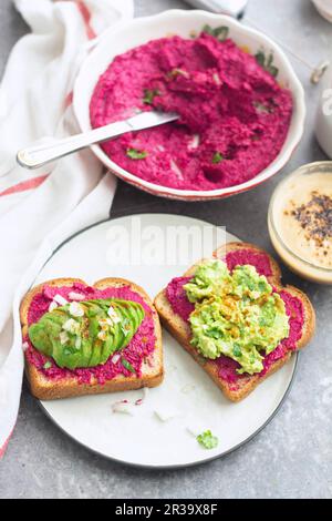 Hummus di barbabietola e purea di avocado sul pane tostato Foto Stock