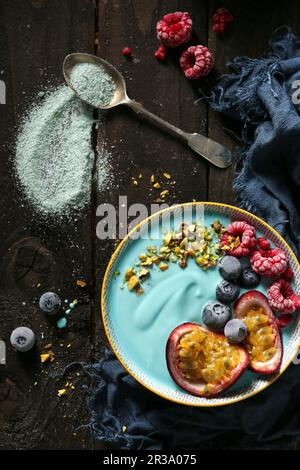 Una ciotola di frullato blu vegano con spirulina, frutta e noci Foto Stock