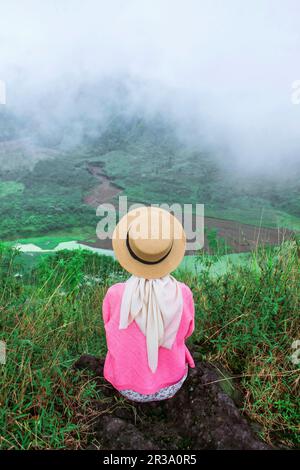 Un viaggiatore femminile si siede godendo la bellezza della natura dall'alto delle montagne Foto Stock