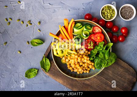 Ciotola di Buddha con ceci, spinaci e altre verdure organiche su fondo di cemento Foto Stock