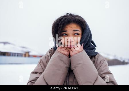 Primo piano di bella ragazza di razza mista si sente fredda e si avvolge in sciarpa di lana lavorato a maglia. Giovane donna congelata cute darkskinned in caldo casual jack Foto Stock