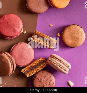 Assortimento di macaron colorati su sfondo viola e marrone Foto Stock