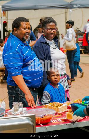 Diversi venditori africani che cucinano e servono vari tipi di cibo di strada a base di pane durante un festival all'aperto Foto Stock