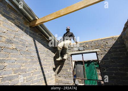 Programma comunitario di Outreach che aiuta a installare tetti in metallo su una piccola casa a prezzi accessibili in una cittadina locale Foto Stock