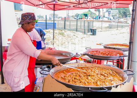 Diversi venditori africani che cucinano e servono vari tipi di cibo di strada a base di pane durante un festival all'aperto Foto Stock