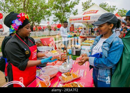 Diversi venditori africani che cucinano e servono vari tipi di cibo di strada a base di pane durante un festival all'aperto Foto Stock