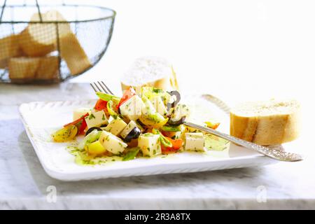 Gouda marinato a dadini con pomodori ciliegini, olive, cipolla, erbe aromatiche e baguette Foto Stock