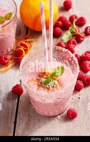 Frullati di lampone e arancia in bicchieri con bacche fresche e cannucce Foto Stock