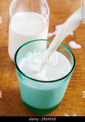 Il latte viene versato in un bicchiere verde Foto Stock