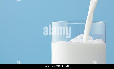 Il latte viene versato nel bicchiere con bolle sullo sfondo azzurro Foto Stock