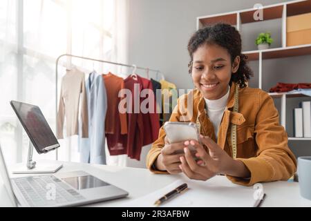 donna telefono e computer portatile progettazione e spedizione di un ordine on-line l'invio di un pacchetto tramite internet dal suo ufficio. tecnologia e logistica con un Foto Stock