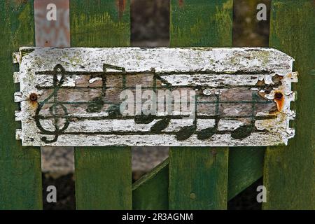 Notelines con note musicali e Clef su un bordo di legno stagionato inchiodato su una recinzione di legno verde Foto Stock