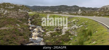 Tortuoso strada di montagna a binario singolo accanto a un ruscello nelle Highlands di Harris vicino Aird Mhige, Harris, Ebridi esterne, Scozia, Regno Unito Foto Stock