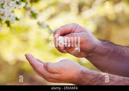 Mani di Mans usando spray antibatterico igienizzante all'aperto Foto Stock