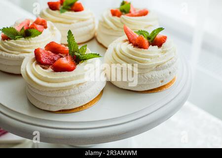 Le dolci meringhe tenue con fragole e menta Foto Stock