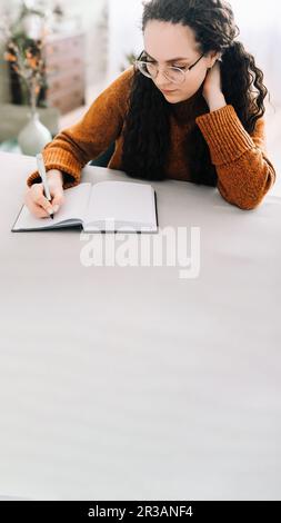 Donna che scrive in copybook. Donna d'affari o giovane studentessa che tiene la penna a mano nella scrittura del giornale del taccuino di carta, prendendo le note che studiano, facendo Foto Stock