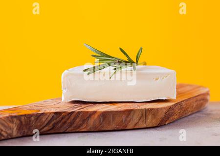 Pezzo di formaggio camembert, primo piano su sfondo giallo Foto Stock