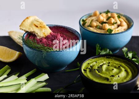 Vari tipi di hummus serviti con verdure fresche e pane pita Foto Stock