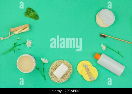 Salviette, shampoo, crema, gua sha e altri accessori su sfondo verde. Vista dall'alto. Copia spazio per il testo. Foto Stock