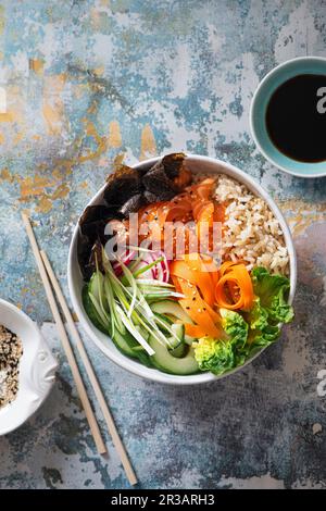 Ciotola di buddha di sushi con salmone, riso di sushi marrone, nori, cetriolo, ravanello, carota e cipollina Foto Stock