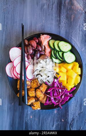 Ciotola di Buddha con riso basmati, mango, tofu fritto, cavolo viola, ravanelli, olive, zenzero sottaceto e alghe Foto Stock