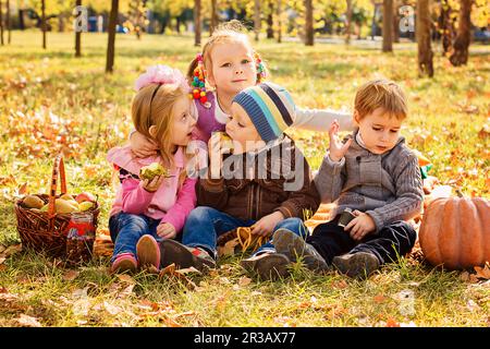 Quattro bambini felici che giocano nel parco autunnale Foto Stock