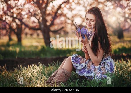 Ritratto di una giovane bella ragazza con un bouquet di lavanda nelle mani nel giardino primaverile Foto Stock