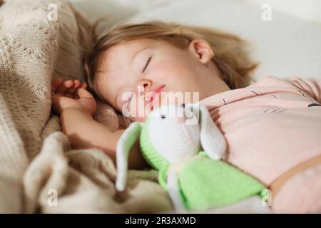 Bambina addormentata. Sonno spensierato bambino piccolo con un giocattolo morbido sul letto. Primo piano di un ritratto Foto Stock