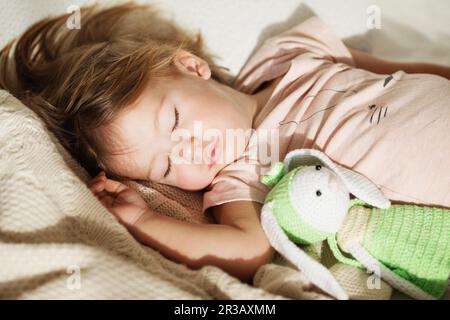 Bambina addormentata. Sonno spensierato bambino piccolo con un giocattolo morbido sul letto. Primo piano di un ritratto Foto Stock