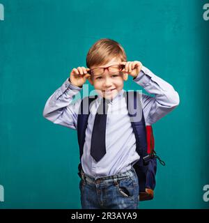 Piccolo ragazzo in occhiali con grande zaino. Scuola, bambino, zaino. Piccolo ragazzo sorridente allegro di nuovo Foto Stock