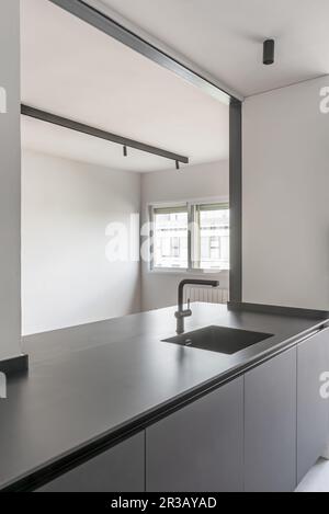 Recentemente installato armadi cucina moderna con un grande portello di servizio aperto al soggiorno e con un lavabo nero incorporato in un countertop dello stesso Foto Stock