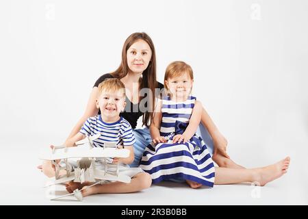 Ritratto di una madre felice e dei suoi due bambini - ragazzo e ragazza. Famiglia felice contro un bianco Foto Stock