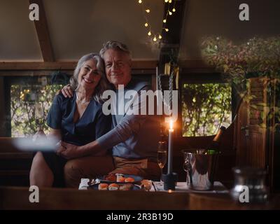 Ritratto di coppia senior avente una cena a lume di candela su una barca in boathouse Foto Stock