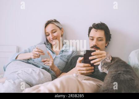 Felice coppia che usa lo smartphone a casa Foto Stock