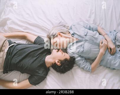 Amare giovane sdraiato sul letto di casa Foto Stock