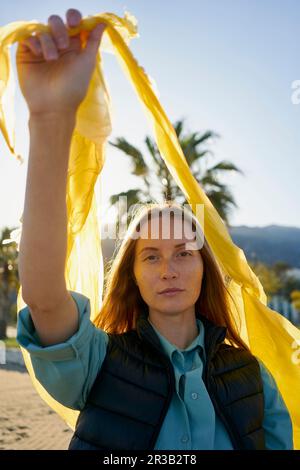 Volontario che tiene il sacchetto di plastica giallo alla spiaggia Foto Stock