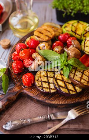 Verdure grigliate sul tagliere su fondo di legno. Verdure alla griglia (peperone colorato, Foto Stock